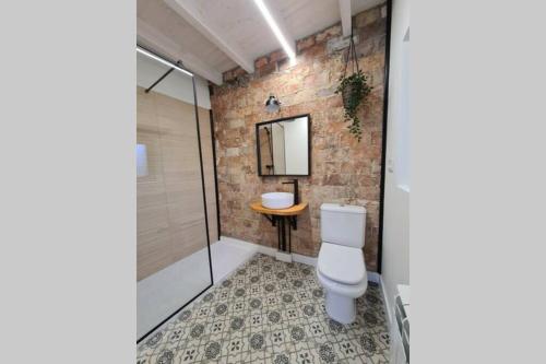 een badkamer met een wit toilet en een bakstenen muur bij Adosado La Concha in Llanes