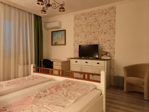 1 dormitorio con 1 cama, TV y silla en Kardos Apartman, en Debrecen