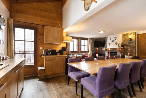 a kitchen and dining room with a wooden table and purple chairs at Chalet Chardons Belvedere in Tignes