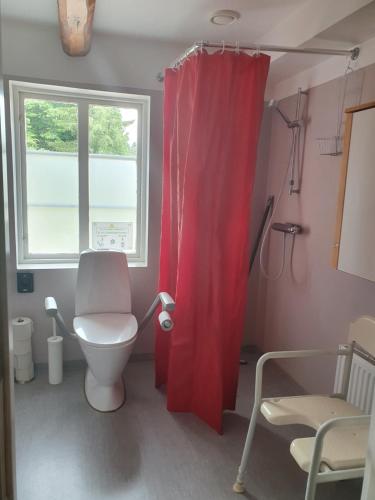 a bathroom with a toilet and a red shower curtain at Klåveröd logi & café in Kågeröd