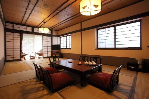 comedor con mesa, sillas y ventanas en Ryokan Yamanoyu, en Minamioguni