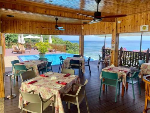 a restaurant with tables and chairs and a pool at Treasure Cove Hotel & Restaurant in Bel Ombre