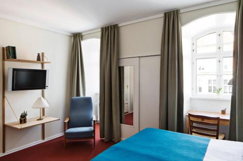 a hotel room with a bed and a chair and a desk at Hotel Alexandra in Copenhagen