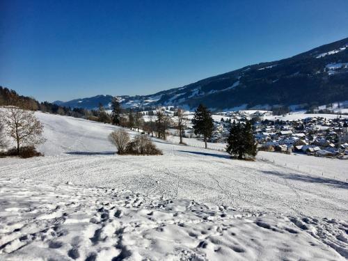 a snow covered hill with a town in the distance at 2 Raum Gästezimmer Prokop in Rettenberg