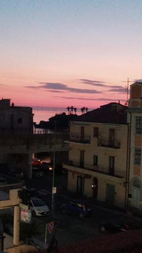 a sunset over a city with a building and palm trees at Ely Sea in Belvedere Marittimo