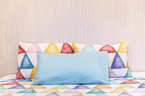 a blue pillow sitting on a bed with colorful pillows at Mola’s Square House in Mola di Bari