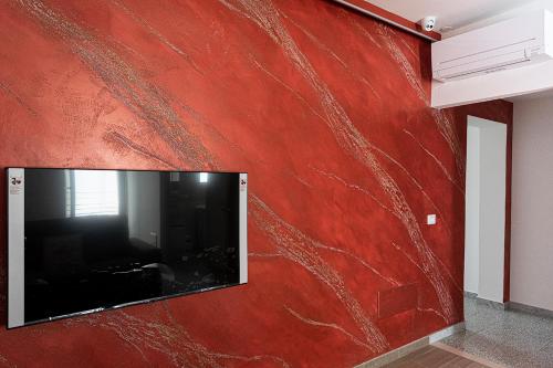 a red wall with a flat screen tv on it at Mola’s Square House in Mola di Bari