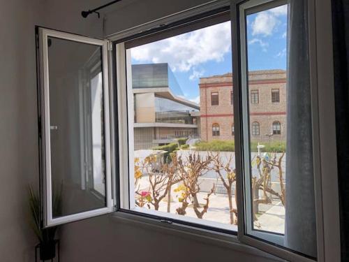 een open raam met uitzicht op een gebouw bij Acropolis Museum Apartment in Athene
