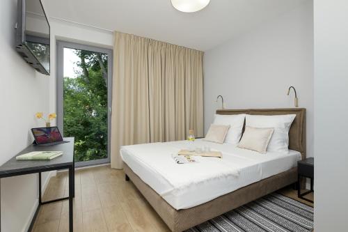 een slaapkamer met een groot wit bed en een raam bij Apartamenty Gryf Rewal in Rewal