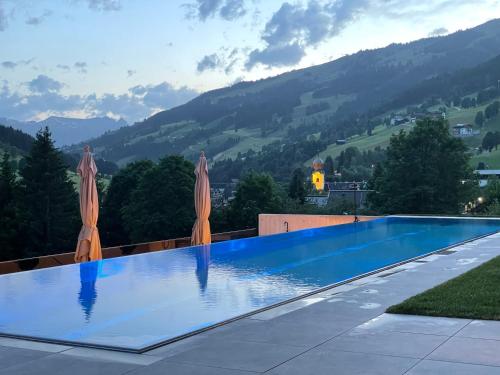 una piscina con 2 sombrillas y una montaña en Appartements Casa Nuova en Saalbach Hinterglemm