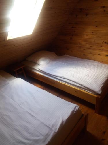 two twin beds in a wooden room with a window at Domek Sara in Przytarnia