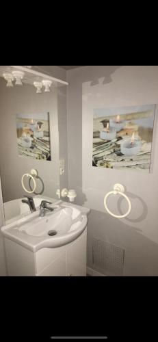 une salle de bain blanche avec un lavabo et un miroir dans l'établissement Le Paradis d’Anny, à Rouffiac-dʼAude