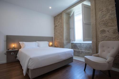 1 dormitorio con 1 cama, 1 silla y 1 ventana en Solar Valadim - serviced apartments en Castelo Branco