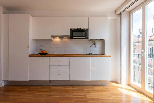 a kitchen with white cabinets and a microwave at Portas Do Bairro in Lisbon