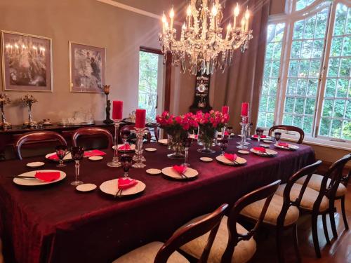 a dining room table with a red table cloth and roses at The Great Gatsby Houghton in Johannesburg