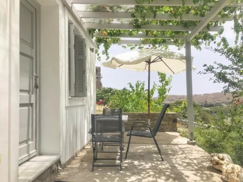 a patio with an umbrella and two chairs and an umbrella at Bright & Cozy Flat - 2 mins to the Town in Andros