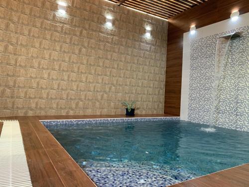 a swimming pool in a room with a brick wall at Oriental Nights Rest House in Al Wāşil