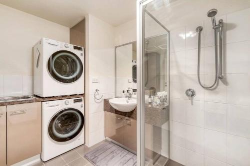 a bathroom with a washing machine and a sink at Sub Penthouse Luxe suit, CBD, secure parking, in Hobart
