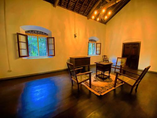 a living room with a table and chairs and a piano at Gileemale Walawwa & Estate in Ratnapura