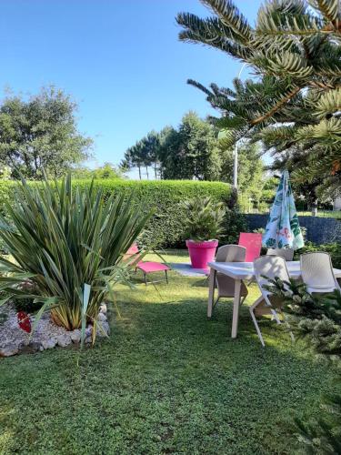 a garden with a table and chairs and a tree at Gite climatisé L'Orée des Landes Proche Center Parcs in Pindères