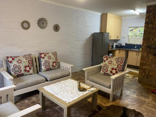 ein Wohnzimmer mit einer Couch und zwei Stühlen und einem Tisch in der Unterkunft Die Kothuis in Malelane