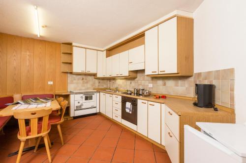 a kitchen with white cabinets and a table in it at Appartement Sonneck in Lappago