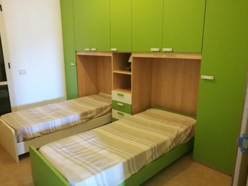 two beds in a room with green cabinets at Casa Vacanza Libone in Nova Siri Marina