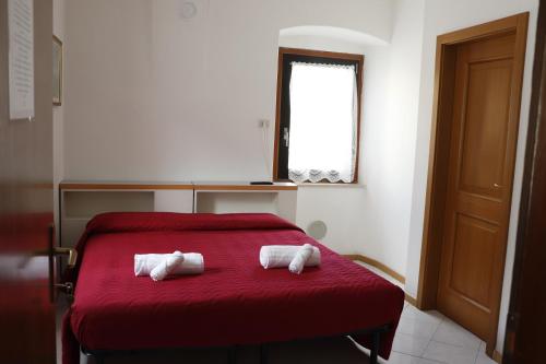 two towels on a red bed in a room at B&B Amico in Comano Terme