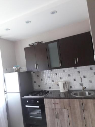 kuchnia z brązowymi szafkami, zlewem i kuchenką w obiekcie Apartment Amest w mieście Batumi