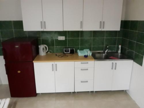 La cuisine est équipée de placards blancs, d'un évier et d'un réfrigérateur. dans l'établissement Apartman Sara, à Sarajevo