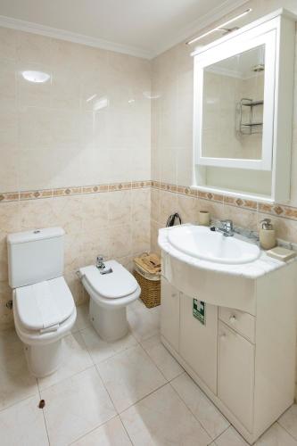 a white bathroom with a toilet and a sink at Apartment Ocean Gardens in Caniço