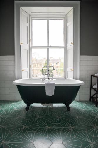 a bath tub in a bathroom with a window at No11 Boutique Hotel & Brasserie in Edinburgh