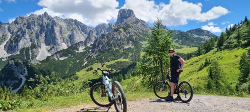 a man standing next to two bikes on a mountain trail at Alpenhaus Donnerkogel in Annaberg im Lammertal