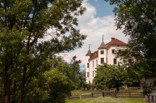 une grande maison blanche avec une clôture et des arbres dans l'établissement Castel Maurn, à San Lorenzo di Sebato