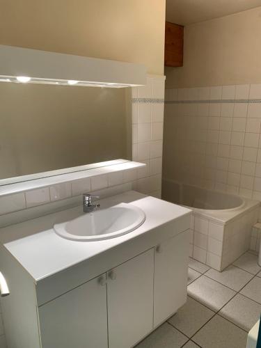 La salle de bains est pourvue d'un lavabo blanc et d'une baignoire. dans l'établissement Appartement centre ville Luz Saint Sauveur T4 pour 10 personnes, à Luz-Saint-Sauveur