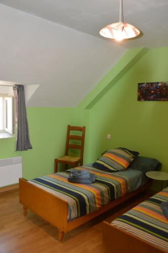 a bedroom with green walls and a bed and a chair at Gîtes des Palanges à l'Aubrac in Sévérac-lʼÉglise