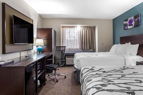 a hotel room with two beds and a desk and a television at Sleep Inn St Robert-Fort Leonard Wood in Saint Robert