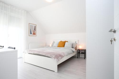 Dormitorio blanco con cama blanca y almohadas de color naranja en WHITE ROOMS ARENA ZAGREB, en Zagreb