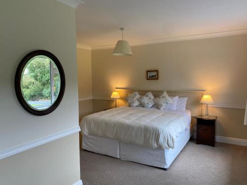 a bedroom with a white bed and a round window at Ardmore House in Clifden