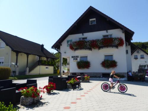 a girl riding a bike in front of a building at House Pox in Plitvička Jezera