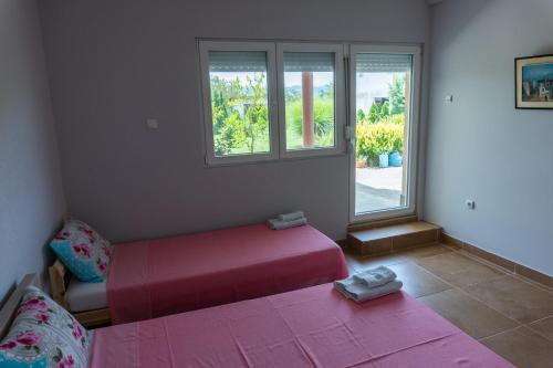 a bedroom with a pink bed and two windows at Villa Katerina & Pool in Gevgelija