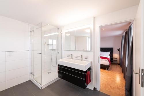uma casa de banho com um lavatório, um chuveiro e uma cama. em Landgasthof Wartegg em Wigoltingen