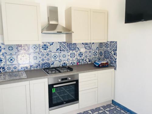 una cucina con armadi bianchi e piastrelle bianche e blu di Villa Zaffiro a Lampedusa