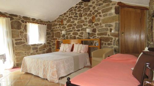 a bedroom with two beds and a stone wall at Quinta da Ribeira in Belmonte