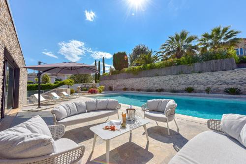 uma piscina com cadeiras e uma mesa ao lado de uma piscina em SERRENDY - Custom villa with swimming pool em Mandelieu-la-Napoule