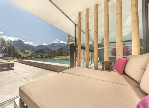 a couch on a balcony with a view of the mountains at Hotel Rodella in Selva di Val Gardena