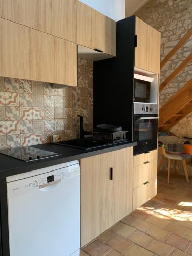 a kitchen with wooden cabinets and a white appliance at Gîte la canopée à Duras - Piscine in Duras