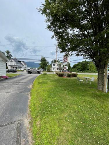 a street with a tree and chairs on the grass at Colonial Motel in North Conway
