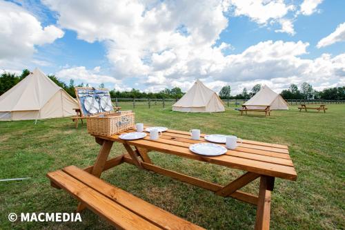 a picnic table with plates and tents in a field at Bell tent glamping at Marwell Resort in Winchester