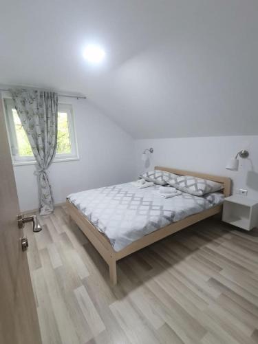 a white bedroom with a bed and a window at New apartment near Plitvice lakes in Smoljanac